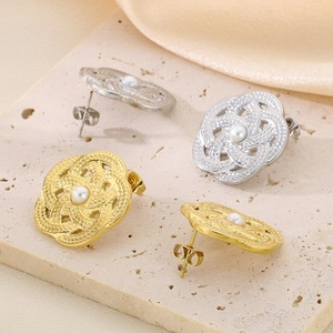Détail de boucles d'oreilles perles évidées en or et argent sur pierre texturée