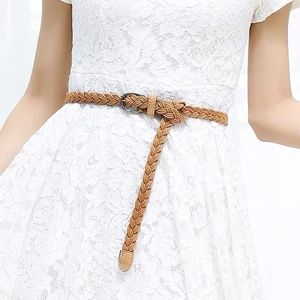Detail of khaki woven skinny belt with silver buckle on a white lace dress