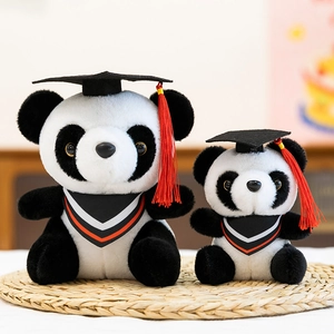 Two graduation panda plush toys with mortarboards and tassels on a natural straw mat