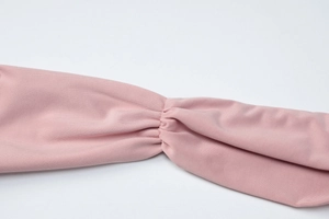 Close-up of pink ribbed knit fabric texture with elegant pleated detailing on the dress