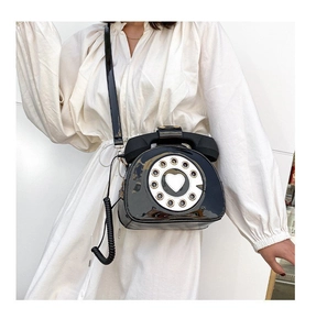 Detail of creative vintage telephone crossbody bag with glossy patent leather and dial