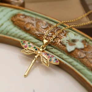 Macro detail of 18K gold dragonfly necklace featuring multicolored zircon wing accents