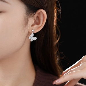 Close-up of butterfly earrings with zircons and drop-shaped stones on female model