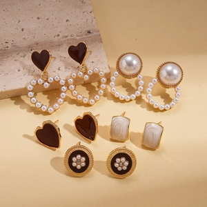 Detailed close-up of 10-piece earring set with pearls and enamel on stone props