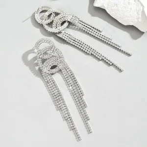 Macro shot of silver long tassel earrings featuring layered rings and paved rhinestones