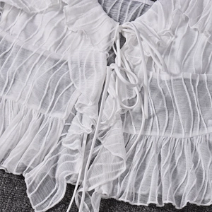 Detail of white striped crop top showing ruffled edges and delicate tie-up front closure
