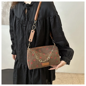 Detail of strawberry print corduroy bag with golden flower chain and leather label