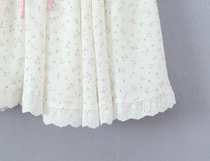 Détail de l'ourlet de la robe avec fleurs roses et broderie papillon avec dentelle blanche