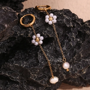 Detailed macro shot of 18K gold-plated earrings with pearls on dark stone surface