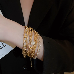 Detailed view of gold multi-layer chain bracelet set with large pearl and rhinestones