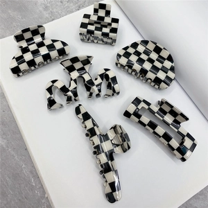 Set of six black and white checkered hair claws in various geometric shapes on white book
