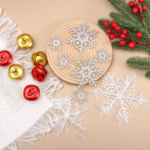 Glittering silver and white snowflake ornaments with festive bells and pine branches