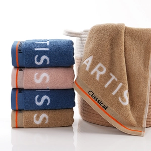 Three-color cotton towel set in blue, pink and brown neatly stacked with a woven basket