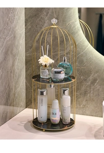 Detailed view of dual-layer golden birdcage cosmetics rack with black marble trays