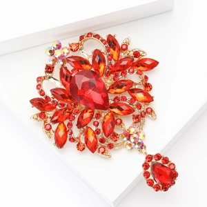 Élégante broche fleur dorée avec cristaux rouges et pendentif goutte sur fond blanc