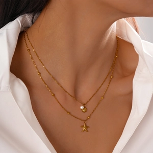 Detail of layered gold necklace featuring a starfish and shell pendant with pearls