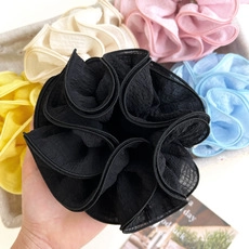 Detail of a ruffled black fabric hair tie with various colorful scrunchies in the background