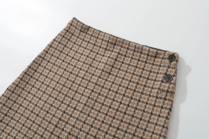Detail des klassischen braunen Hahnentrittmusters mit dunklen Knöpfen und Tweed-Textur