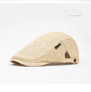 Detail of beige woven straw ivy cap with metal logo and adjustable snap closure