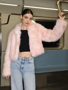 Détail de la texture d'une veste rose en fausse fourrure portée par un mannequin urbain