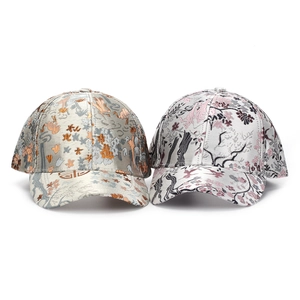 Detail of floral and bird embroidery on structured satin baseball caps in traditional style