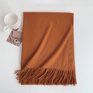 Detailed view of folded brown soft cashmere-like scarf with fringe near a mug and card
