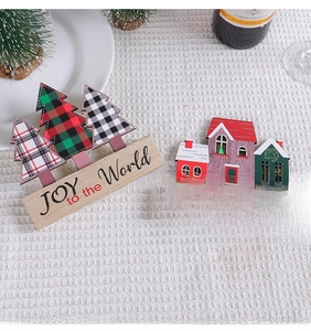 Close-up of wooden Christmas tree and house ornaments on a cozy white knit background