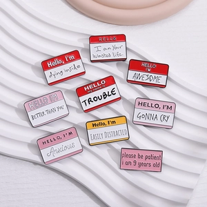 Detailed macro shot of nine enamel pins with motivational quotes on a wavy white tray