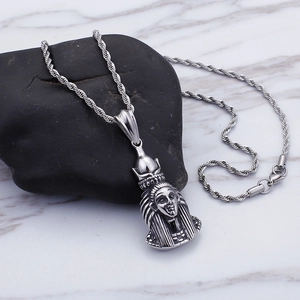 Macro shot of silver Pharaoh pendant on a dark pebble with a white marble background