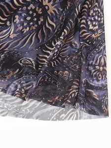 Gros plan sur le tissu en tulle avec motifs paisley violet et or sur un haut sombre