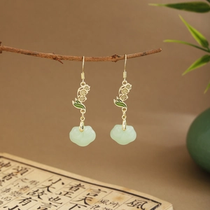 Detail of green fan-shaped tassel earrings with gold hooks on a traditional background
