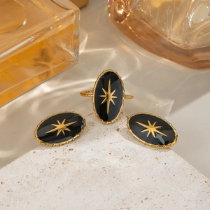 Macro shot of black star jewelry set with oval earrings and ring on a stone