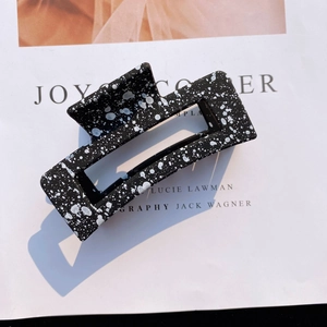 Detail of matte black acrylic rectangular hair claw clip with white splatter pattern