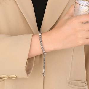 Gros plan d'un bracelet à billes argentées avec fermoir réglable sur le poignet