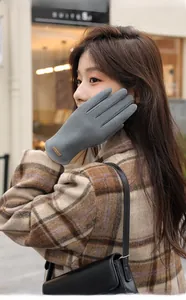 Detail of grey winter gloves with touch-screen fingertip and branded leather patch