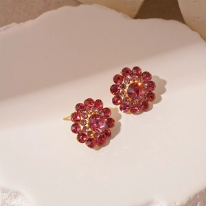Macro detail of luxury floral stud earrings with pink crystals and gold finish
