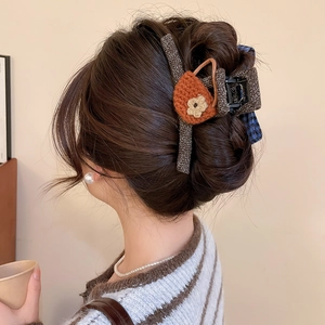 Detail of Korean style knit bow hair claw clip with orange crochet flower on woman hair