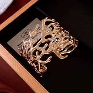 Macro shot of gold coral branch open cuff bracelet in a black velvet jewelry gift box
