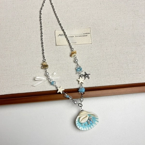 Macro shot of seashell pendant and blue star details on a layered beaded necklace