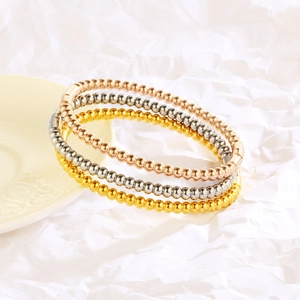 Three beaded bracelets in gold, silver and rose gold shown on a ceramic dish