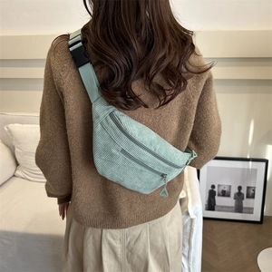 Minimalist mint green corduroy waist bag with adjustable strap worn by a model