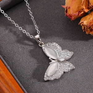 Macro detail of silver bow pendant featuring shell stone and micro-pave crystals on velvet