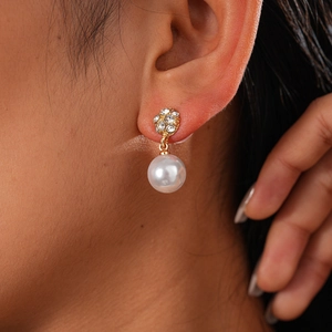 Detail von goldenen Perlenohrringen mit Diamanten am Ohrläppchen für einen Luxus-Look