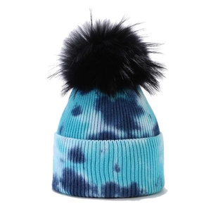Blue and white tie-dye knit beanie featuring a large black faux fur pom pom