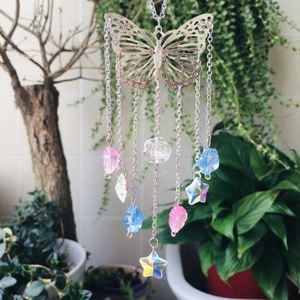 Detail of butterfly suncatcher with colorful crystal prisms and stars against green plants