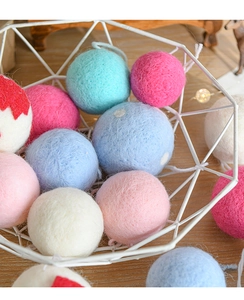 Detail of colorful wool felt balls piled in a white wire basket for Christmas decor