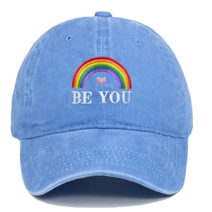 Close-up of rainbow and BE YOU embroidery on washed blue cotton baseball cap