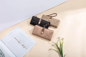 Detailed view of long vintage wallets in black, taupe, and pink with leaf embossed metal buckle