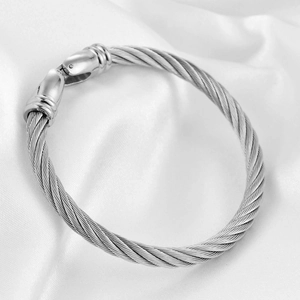 Silver stainless steel cable bangle with twisted metal design on white silk background