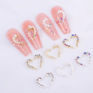 Macro shot of heart-shaped nail charms with pearls and rhinestones in gold and silver